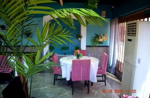 a dining room with a white table and pink chairs at Le Relais de Bamako in Bamako