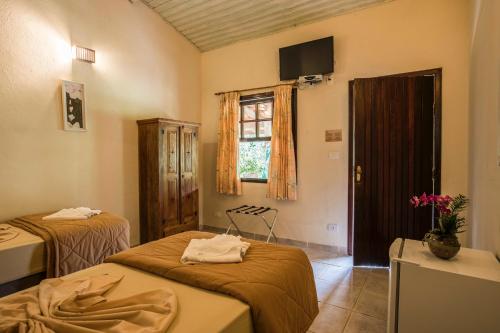 a room with two beds and a tv and a window at Pousada das Cavernas in Iporanga