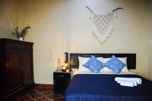 a bedroom with a bed with blue and white pillows at Ave del Paraiso Guest House in Antigua Guatemala