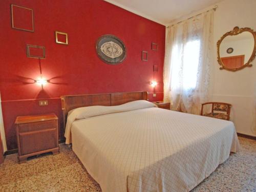 Casa Vacanze "Al Castello" Venezia في البندقية: غرفة نوم بحائط احمر مع سرير ونافذة