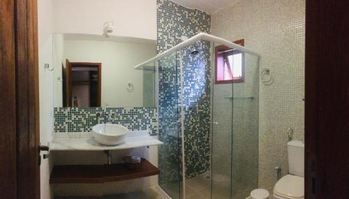 a bathroom with a sink and a glass shower at Picollo Bambino Suítes Ilhabela in Ilhabela