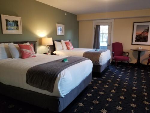 a hotel room with two beds and a chair at The Inn on Mount Desert in Bar Harbor
