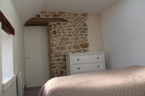 Le Grenier في Mauléon: غرفة نوم بسرير وجدار حجري