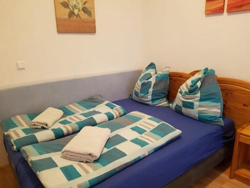 Bett mit blauer und weißer Bettwäsche und Kissen in der Unterkunft Ferienwohnung in Diehlo in Eisenhüttenstadt