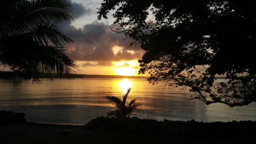 un tramonto su un corpo di acqua con palme di Santo Seaside Villas a Luganville