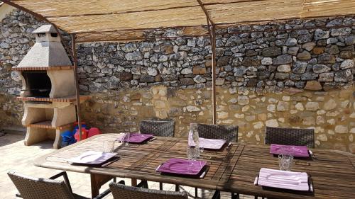 une table en bois avec des chaises et un mur en pierre dans l'établissement Bienvenue Chez Romane, à Aiguèze