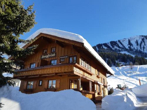 ein großes, schneebedecktes Holzgebäude in der Unterkunft Das Bergfried - Urlaub zentral und ruhig! in Riezlern