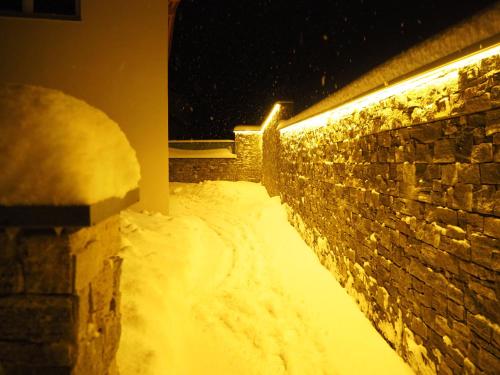 a snow covered hallway with a brick wall and a light at Jochberg Hoamatl in Jochberg