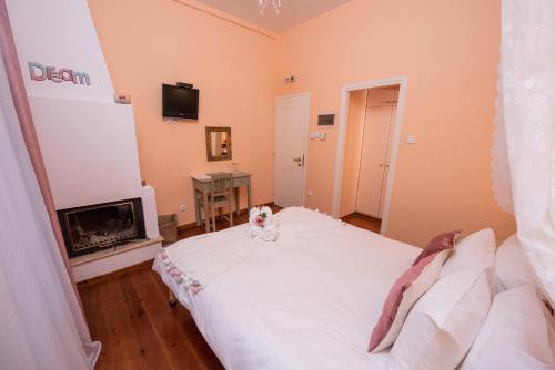 a bedroom with a white bed and a fireplace at Archontiko Argyro in Makrinítsa