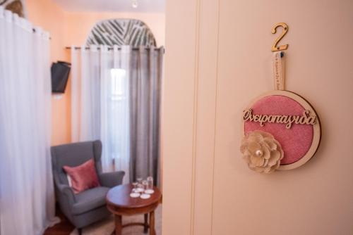 a living room with a chair and a clock on the wall at Archontiko Argyro in Makrinítsa