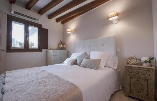Un dormitorio con una gran cama blanca y una ventana en La Casa del Tránsito, en Toledo
