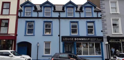 een blauw gebouw op een straat met auto's voor geparkeerd bij The Stonehouse, in the heart of Ballycastle in Ballycastle