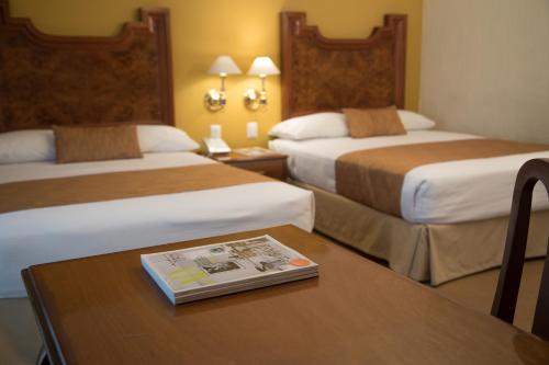 a hotel room with two beds and a book on a table at Country Plaza in Guadalajara