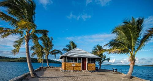 eine kleine Hütte am Strand mit Palmen in der Unterkunft Dua Dua Beach Resort in Rakiraki