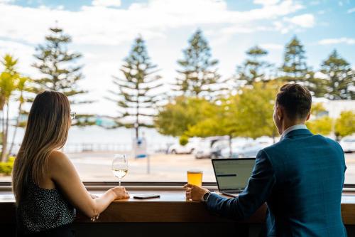 a man and a woman sitting at a table with a laptop at Port Lincoln Hotel in Port Lincoln