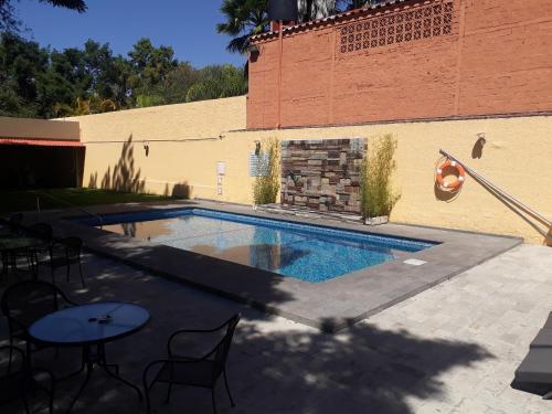 a swimming pool with tables and chairs next to a building at Country Plaza in Guadalajara