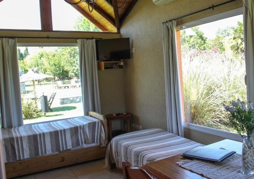 Habitación con cama, mesa y ventana en Cabañas Los Sauces en Tandil