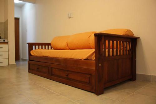 una cama de madera con una sábana naranja encima en Complejo Antares en San José
