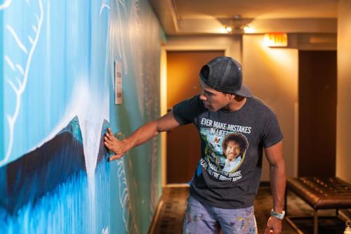 a man is painting a wall in a room at VIVE Hotel Waikiki in Honolulu