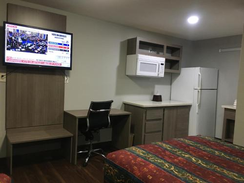 a hotel room with a bed and a flat screen tv at Travel Inn & Suites in Humble