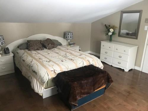 um quarto com uma cama, 2 cómodas e um espelho em Gite Duchenier em Saint-Narcisse-de-Rimouski