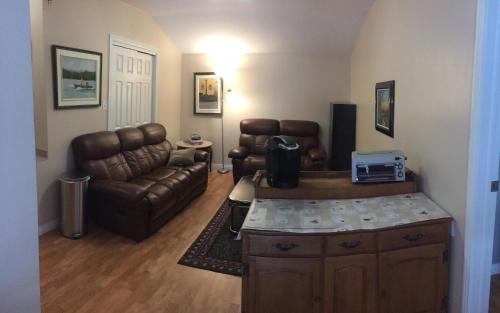 a living room with a leather couch and a table at Gite Duchenier in Saint-Narcisse-de-Rimouski