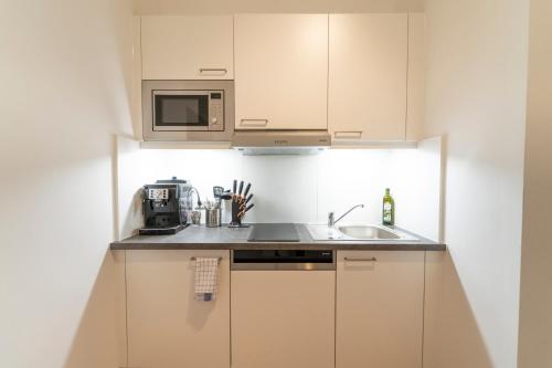 eine Küche mit einer Spüle und einer Mikrowelle in der Unterkunft Agnes I levestate in Wien