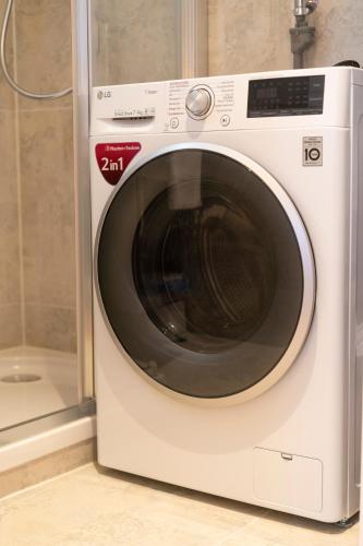 a white washing machine sitting next to a shower at josef's home I Renaissance Studio in Vienna