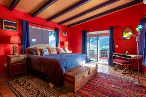 sypialnia z czerwonymi ścianami, łóżkiem i biurkiem w obiekcie Chuck's Cabin in a Joshua Tree Community w mieście Twentynine Palms