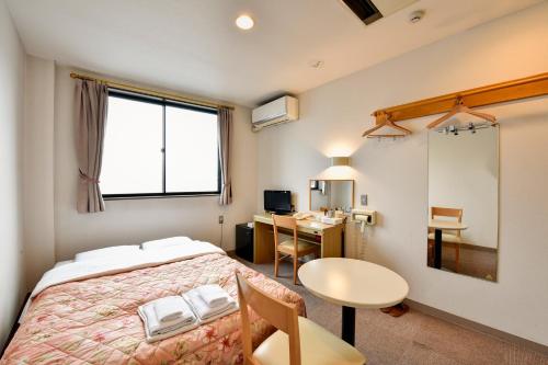 a bedroom with a bed and a table and a desk at Hotel Hana in Takayama