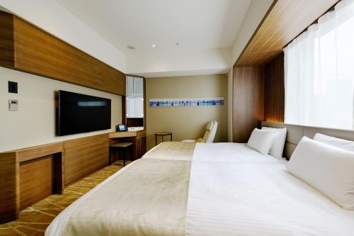 Habitación de hotel con 2 camas y TV de pantalla plana. en remm plus Ginza, en Tokio