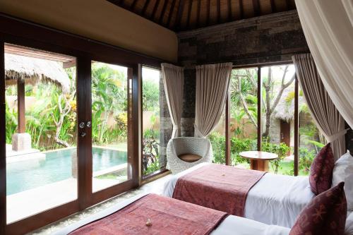 a bedroom with two beds and a view of a pool at WakaGangga in Tabanan