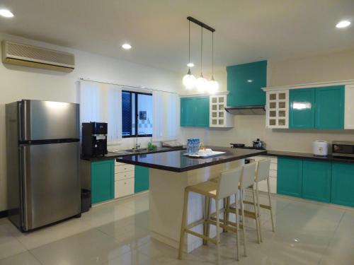 eine Küche mit grünen Schränken und einem Kühlschrank aus Edelstahl in der Unterkunft Rimbun Suites & Residences in Bandar Seri Begawan
