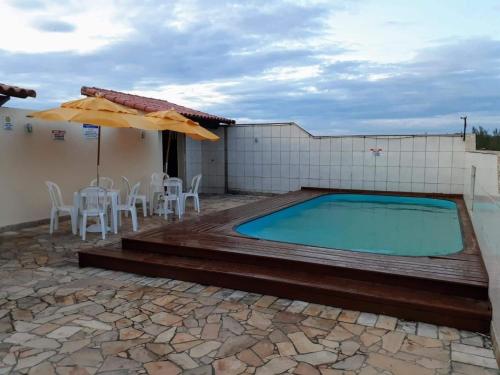 une piscine avec une table, des chaises et un parasol dans l'établissement Recanto no Caribe, à Arraial do Cabo