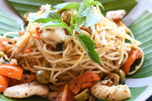 a plate of pasta with vegetables and parsley on it at Bruga Villas Restaurant and Spa in Selong Belanak