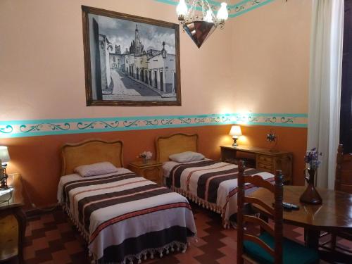 a hotel room with two beds and a table at Casa Relox 23 in San Miguel de Allende