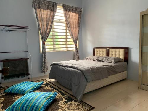 a bedroom with a bed and a window and pillows at Pak Lang Homestay in Kampung Gurun