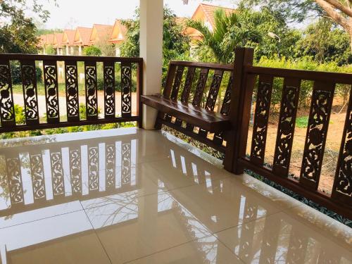 a wooden bench on a porch with a fence at Suan Luang Garden View in Nong Khai