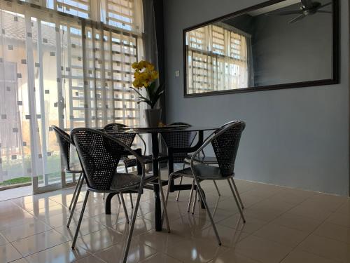 a dining room table with chairs and a vase of flowers at Pak Lang Homestay in Kampung Gurun