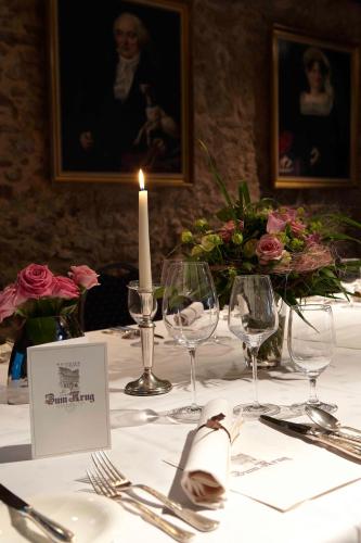 a table with a candle and wine glasses on it at Hotel und Weinhaus Zum Krug in Eltville