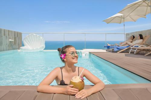 a girl holding a coconut in a swimming pool at Holiday Beach Hotel Danang in Danang