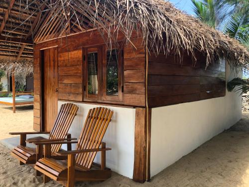 two chairs sitting in front of a hut on the beach at Kadjan villa in Arugam Bay