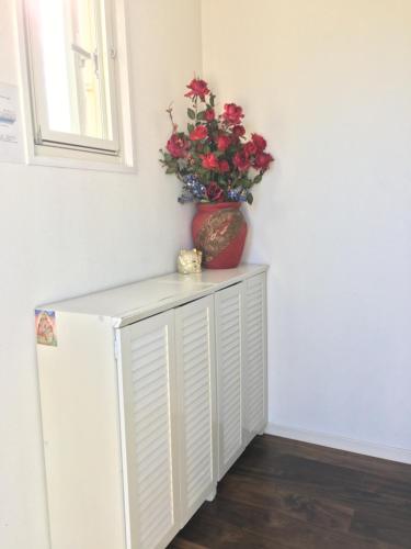 a red vase with a plant on top of a refrigerator at 駅近-最大収容9人JR小岩駅まで徒歩圏Leo小岩301 in Tokyo