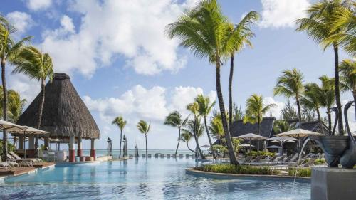 a swimming pool with palm trees and the ocean at Ambre - Adults only in Belle Mare