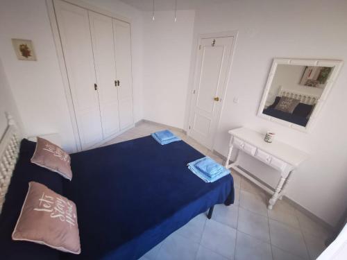 um quarto com uma cama azul e uma mesa branca em Cosy apartment Arenal Bol em Calpe