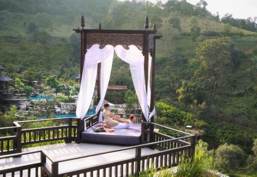 a woman sitting in a canopy bed with a child at Panviman Chiang Mai Spa Resort in Mae Rim