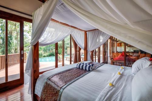 a bedroom with a canopy bed in a house at The Grand Bakas Jungle Retreat Villa in Klungkung