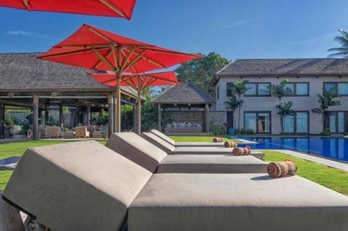 a house with a pool and a red umbrella at Villa Takali - CFC Certified in Pacific Harbour