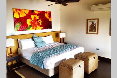 a bedroom with a bed with a painting on the wall at Villa Takali - CFC Certified in Pacific Harbour