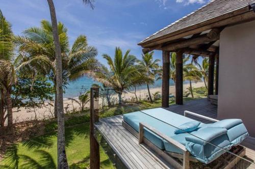 a bed on a wooden deck with a view of the beach at Villa Takali - CFC Certified in Pacific Harbour